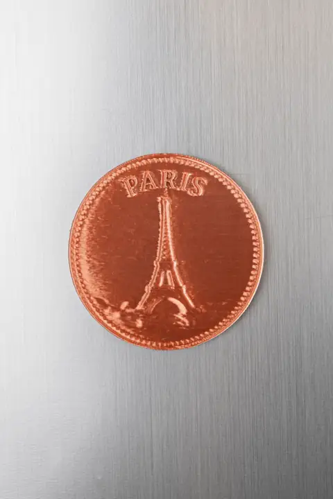 Moeda-souvenir de Paris com acabamento cobre, sobre uma base metálica.